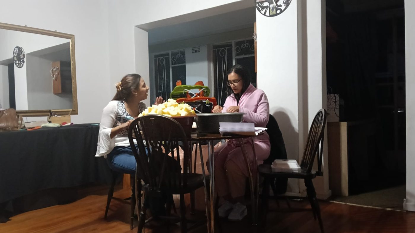 Two women seated at a table with a bowl of fruit, preparing for the day
