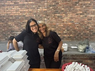 Two team members smiling together behind the serving table
