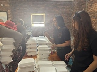 Team members packing stacked meal containers